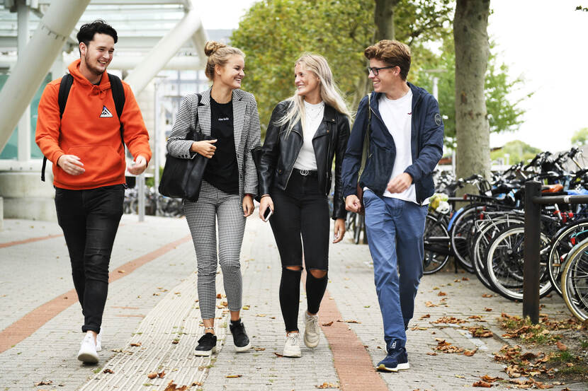 Studenten lopen buiten lachend naast elkaar