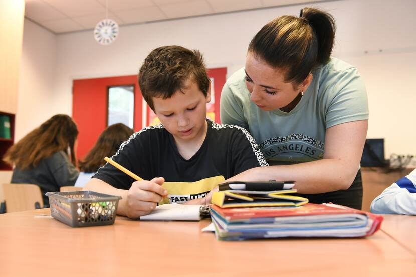 lerares helpt leerling met werk